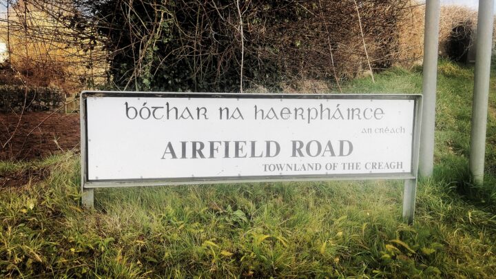 Signage in Irish and English marking Airfield Road close to the bridge that links the two halves of the former Toome Airfield, Co. Antrim.