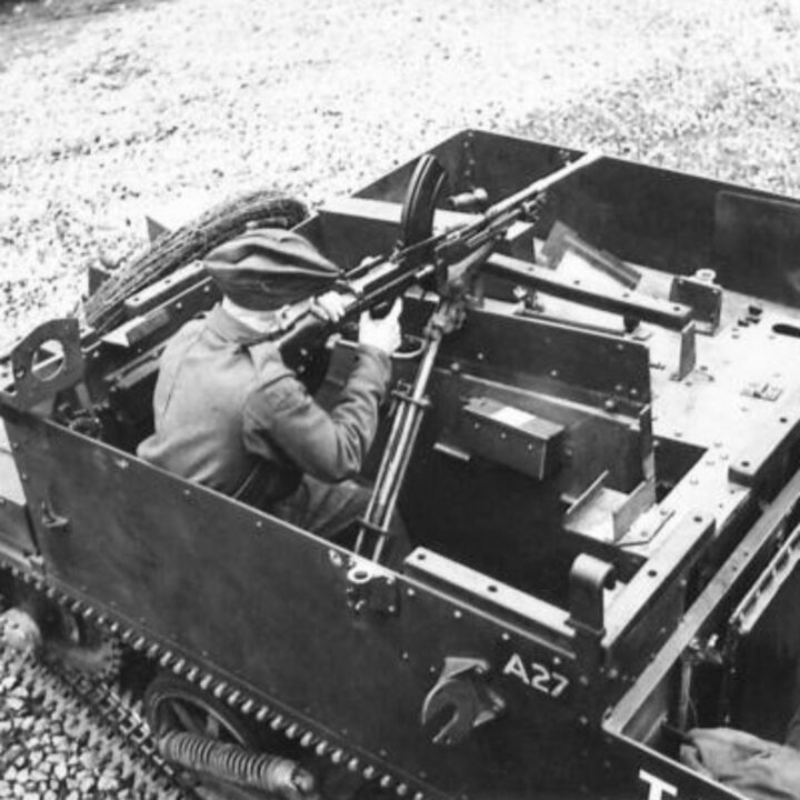 Photograph showing gun firing mountings on a Universal Carrier in Northern Ireland. A soldier demonstrates firing a Bren Gun to the left-hand side.