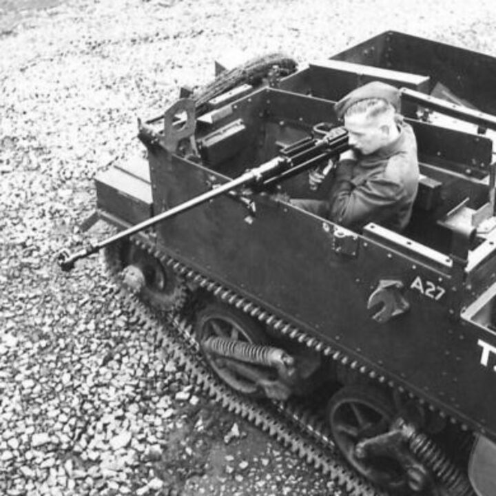 Photograph showing gun firing mountings on a Universal Carrier in Northern Ireland. A soldier demonstrates firing a Boys Anti-Tank Rifle to the right-hand side.