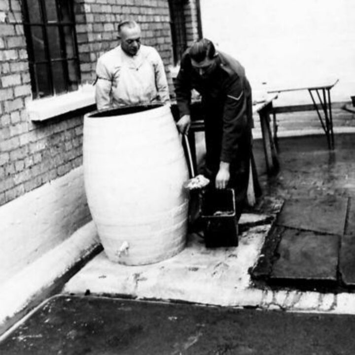 Soldiers retrieving used greasy water from a storage barrel at the Royal Army Service Corps depot in Belfast.