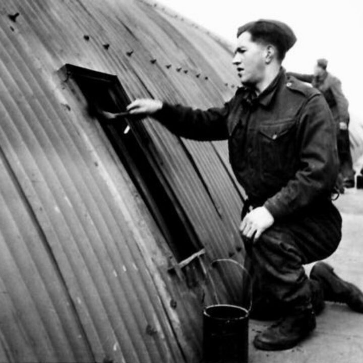 A member of The Pioneer Corps applying a coat of paint to a hut in Northern Ireland.