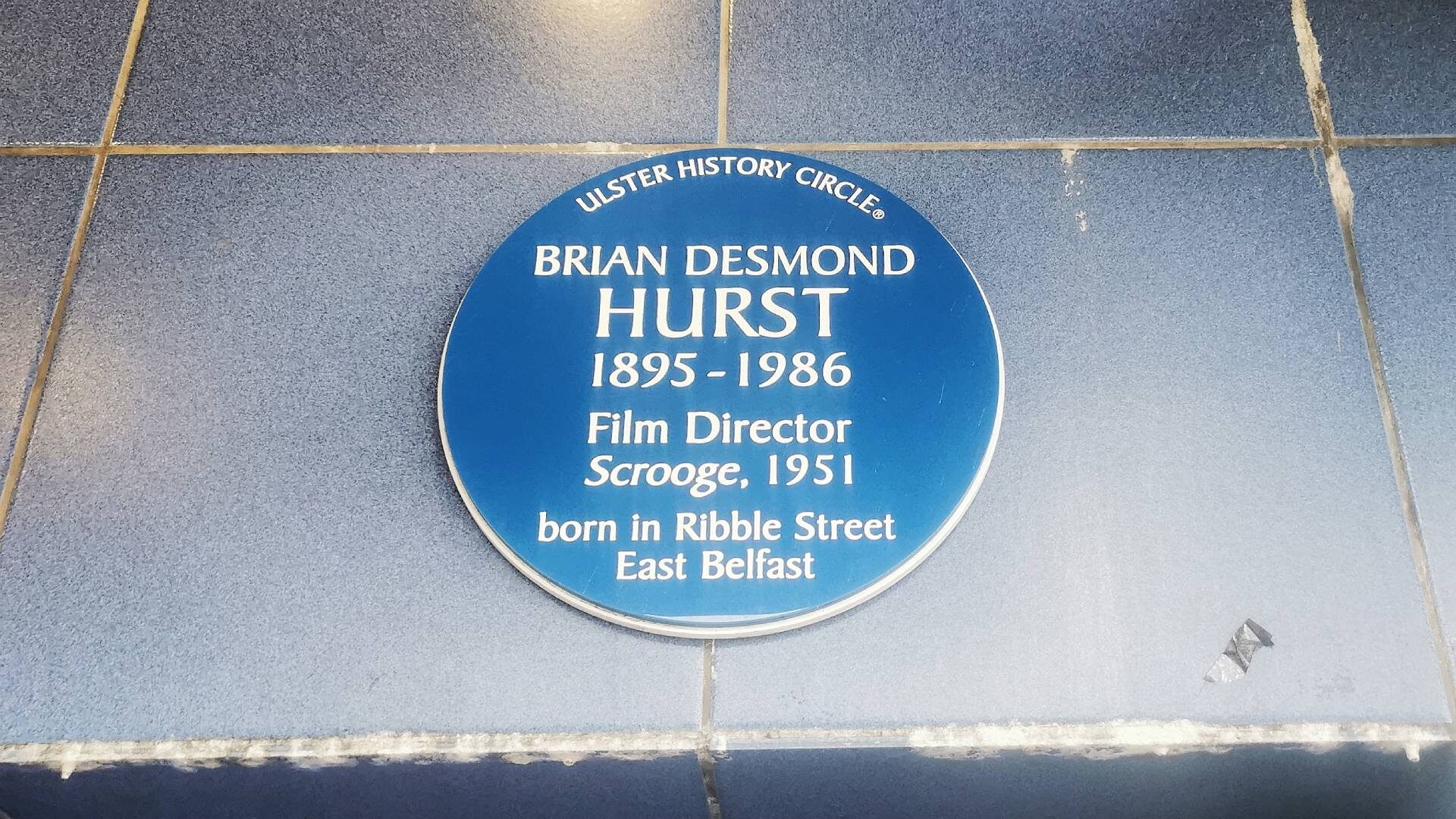 Ulster History Circle blue plaque commemorating the life and work of Belfast-born film director Brian Desmond Hurst on the front of the Strand Arts Centre, a cinema and entertainment venue in East Belfast.