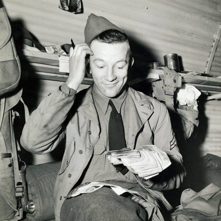 A soldier of the United States Army becomes accustomed to British currency on a payday in Northern Ireland. Photo taken by Larry Williams on 16th March 1942.