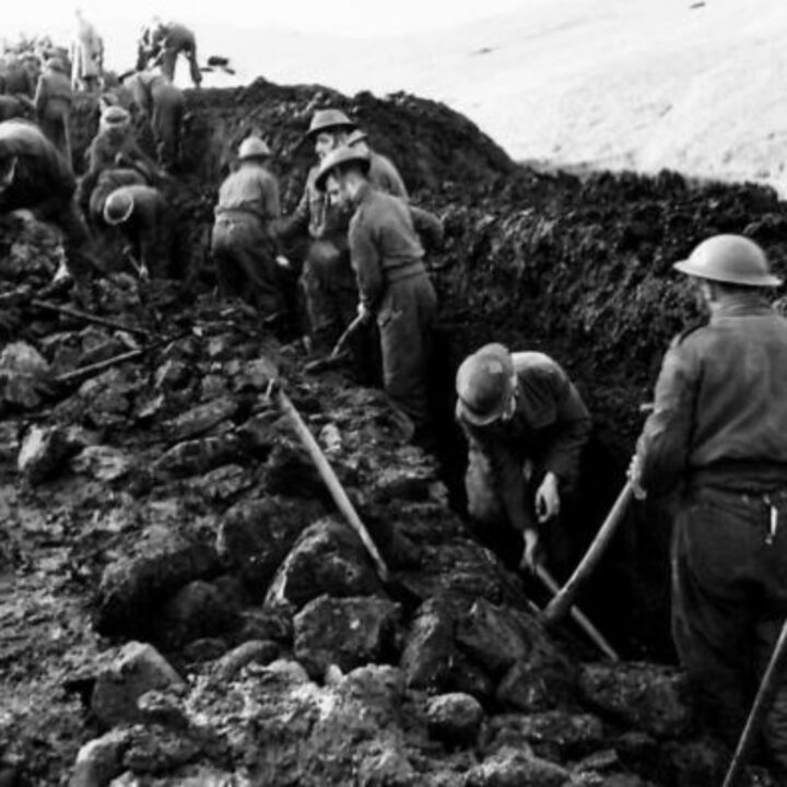 Members of 297, 582, 583, and 584 Companies, Kent Corps Troops, Royal Engineers cutting a new road through the Sperrin Mountains and Templemoyle, south of Dungiven, Co. Londonderry. Soldiers dig a drainage ditch using shovels and pick-axes.