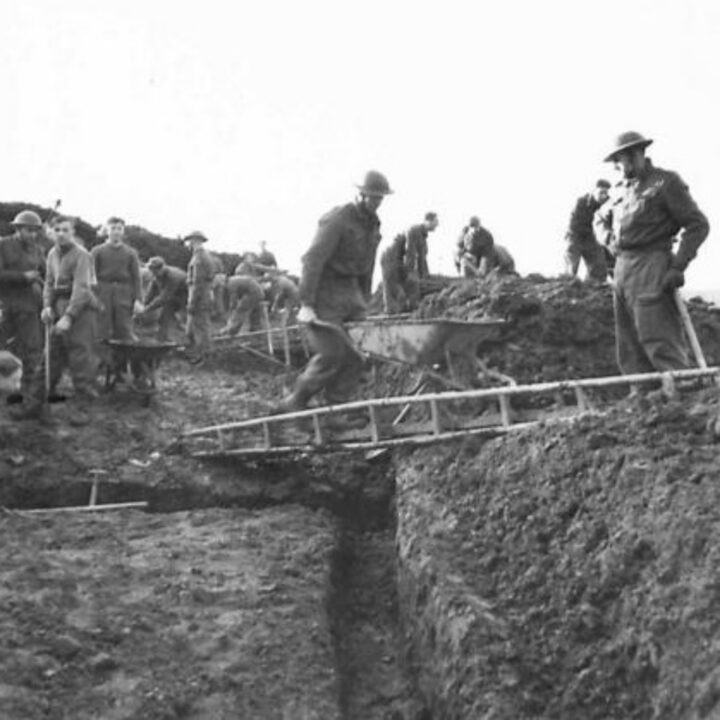 Members of 297, 582, 583, and 584 Companies, Kent Corps Troops, Royal Engineers cutting a new road through the Sperrin Mountains and Templemoyle, south of Dungiven, Co. Londonderry. A soldier crosses a track bridge with a barrow full of loose earth.