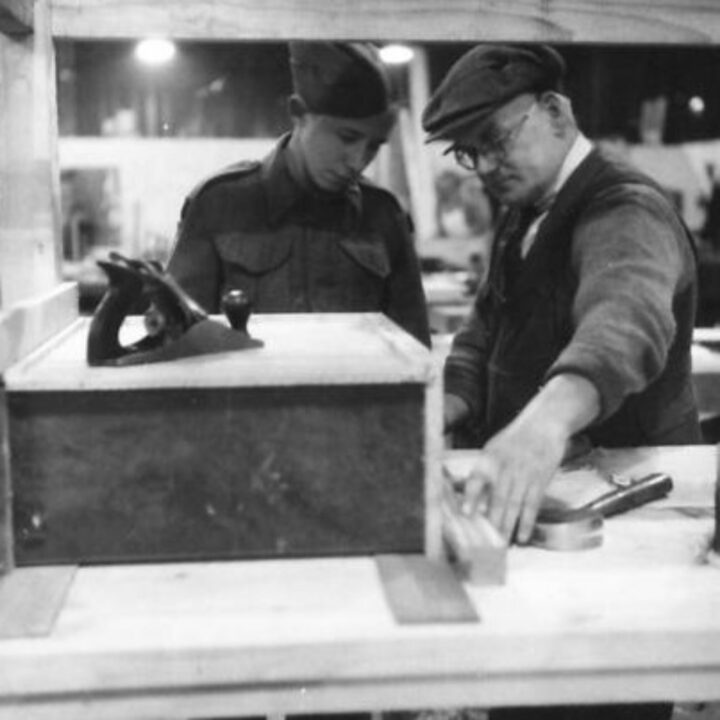 Craftsman G. Reid of Belfast under training from carpenter W. Robson of Newcastle-upon-Tyne, England at a Royal Electrical and Mechanical Engineers base workshop at Kinnegar Barracks, Holywood, Co. Down.