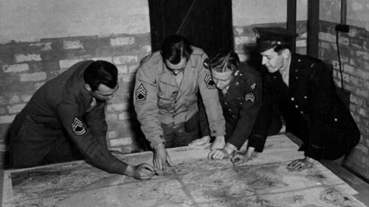 Technical Sergeant Michael Kruge, Technical Sergeant Pari Hooper, Sergeant Arnold Bohleber, and First Lieutenant Bill Wright plotting a map in the Crew Briefing Room at U.S.A.A.F. Station 236, Toome Airfield, Co. Antrim on 21st September 1943.