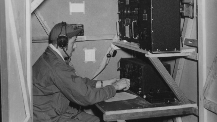 Radio Operator Corporal Paul Carrion operating radio equipment in the Harwell Box, a device used in procedure training to simulate the radio compartment of a bomber, at U.S.A.A.F. Station 236, Toome Airfield, Co. Antrim on 21st September 1943.