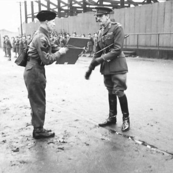 Brigadier P.H. Hansen V.C. presents a certificate for devotion to duty during an air raid to Lance Sergeant Lisle C. Chute. The event is the presentation of the St. Patrick's Day Shamrock by Brigadier P.H. Hansen V.C. to members of 31st Battalion Royal Ulster Rifles, U.S. Army Officers of Irish descent, and members of the Auxiliary Territorial Service at Dunmore Park, Belfast.