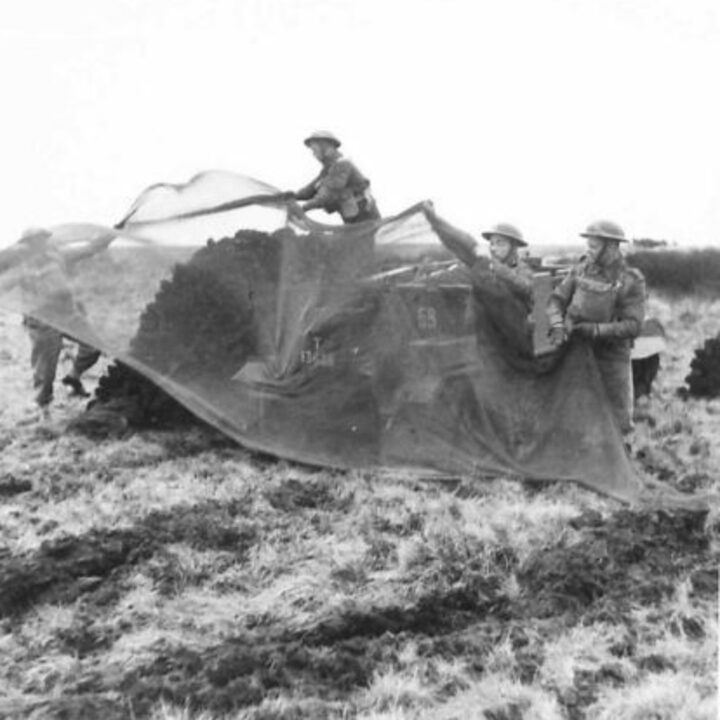 Soldiers of 1/5th Battalion, The Welsh Regiment halt their Universal Carrier by a peat stack and cover it with camouflage near Newry, Co. Down.