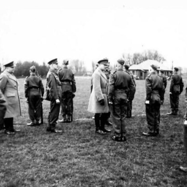 Brigadier G.F. Watson D.S.O. looks on as His Royal Highness The Duke of Gloucester speaks with a member of 9th Battalion, Gloucestershire Regiment at Victoria Park, Belfast.