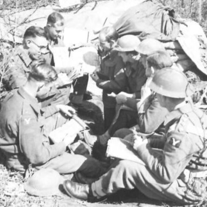 Lieutenant Colonel Slane M.C. (Commanding Officer of 2nd Battalion, Royal Inniskilling Fusiliers) holding maps holds a conference with Company Commanders including Major J.B. Miller and Captain E.T. Irving (Adjutant). 2nd Battalion, Royal Inniskilling Fusiliers celebrate St. Patrick's Day during their time in the fighting line at Anzio, Italy.