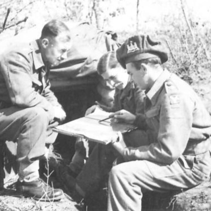 Lieutenant Colonel Slane M.C. (Commanding Officer of 2nd Battalion, Royal Inniskilling Fusiliers) holding maps holds a conference with Company Commanders Major J.B. Miller and Captain E.T. Irving (Adjutant). 2nd Battalion, Royal Inniskilling Fusiliers celebrate St. Patrick's Day during their time in the fighting line at Anzio, Italy.