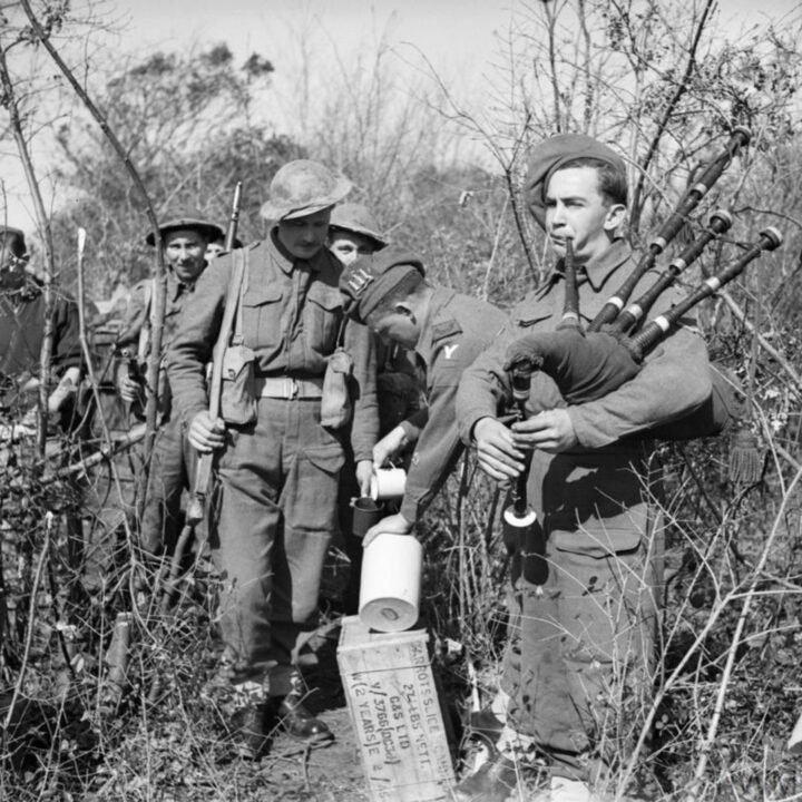 Regimental Sergeant Major Kilduff of Lucan, Dublin, Ireland issues a rum ration to Fusilier Rogers of Drumsteeple, Co. Londonderry, and Lance Corporal Niland of Devenish Road, Dublin Ireland plays the pipes. 2nd Battalion, Royal Inniskilling Fusiliers celebrate St. Patrick's Day during their time in the fighting line at Anzio, Italy.
