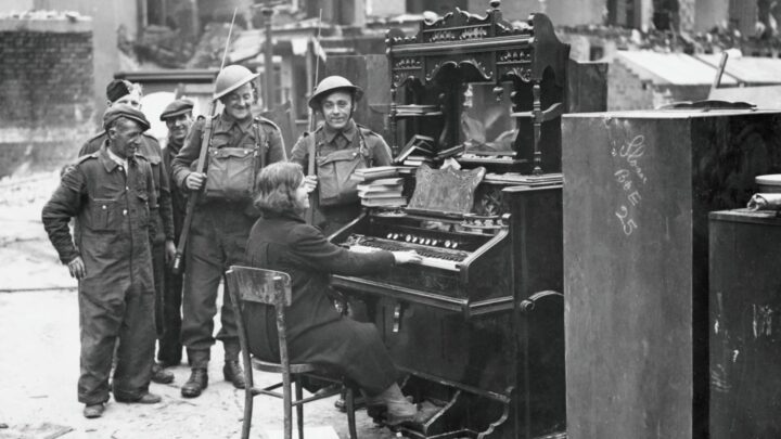 Local residents and soldiers take a break from clearing up in the aftermath of the Belfast Blitz for an impromptu organ recital on a salvaged instrument on York Road, Belfast, Belfast.