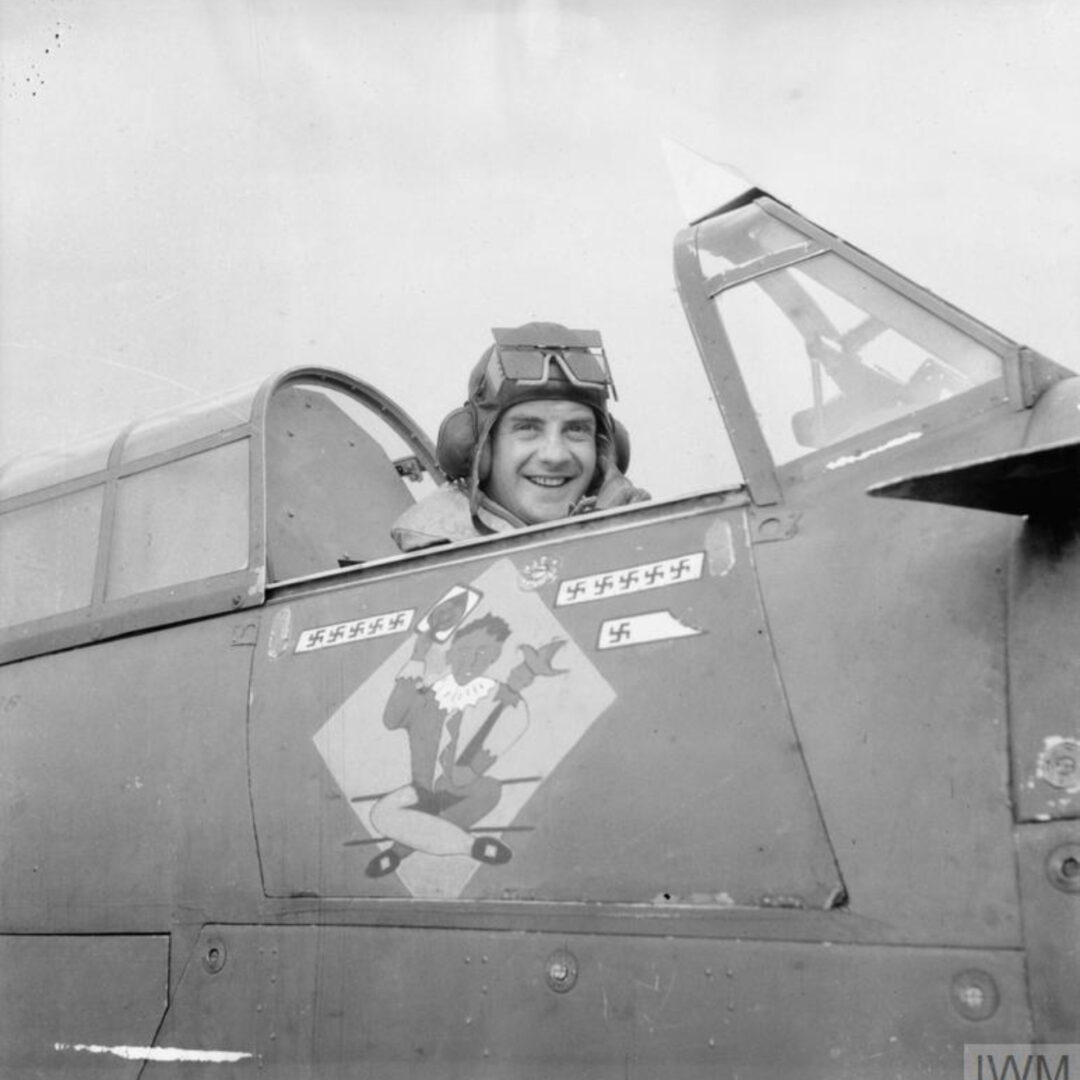 Squadron Leader John William Charles Simpson D.F.C., Commanding Officer of R.A.F. 245 Squadron in Hawker Hurricane I W9145 DX-L at R.A.F. Aldergrove, Co. Antrim. His plane shows a jester painting and the mark of his 11th victory which came in Northern Ireland on 8th April 1941. His 12th would follow the next day.