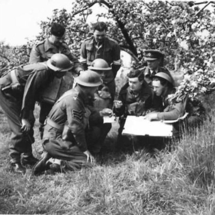 Officers of 2nd Battalion, Royal Inniskilling Fusiliers hold a company commander conference beneath an apple tree in blossom in Northern Ireland.