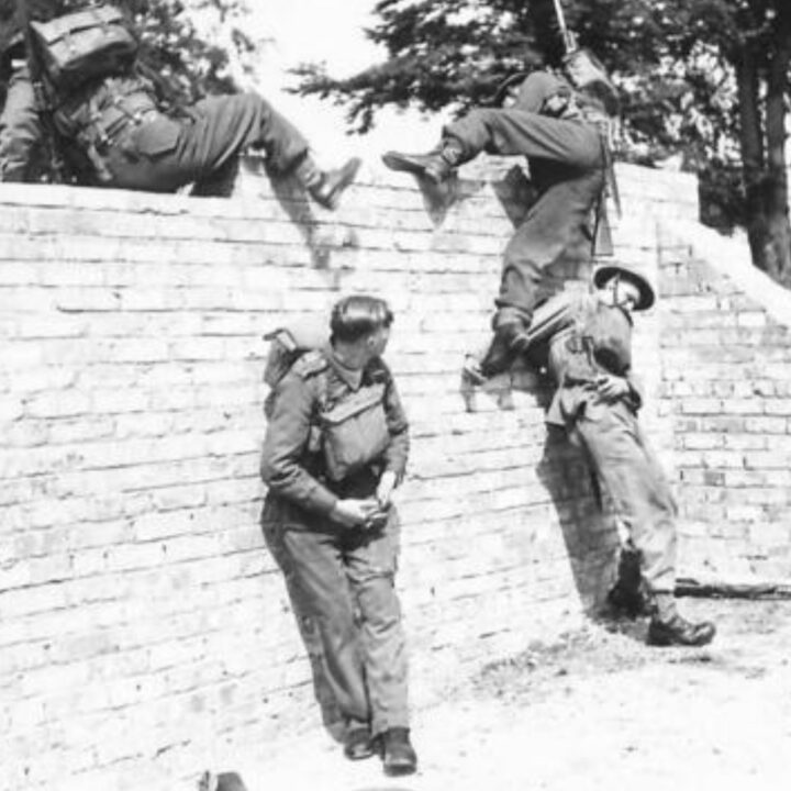 Soldiers of 8th (Nottinghamshire) Battalion, The Sherwood Foresters, 148th Independent Infantry Brigade cross a high brock wall during a training exercise near Muckamore, Co. Antrim.