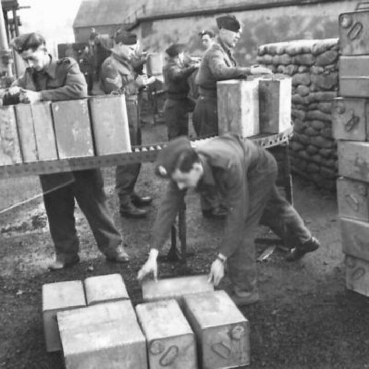 Members of the Auxiliary Territorial Service off-load empty petrol cans on to a roller conveyor where they are inspected, repaired, cleaned, and refilled at a petrol distributing centre in Northern Ireland.