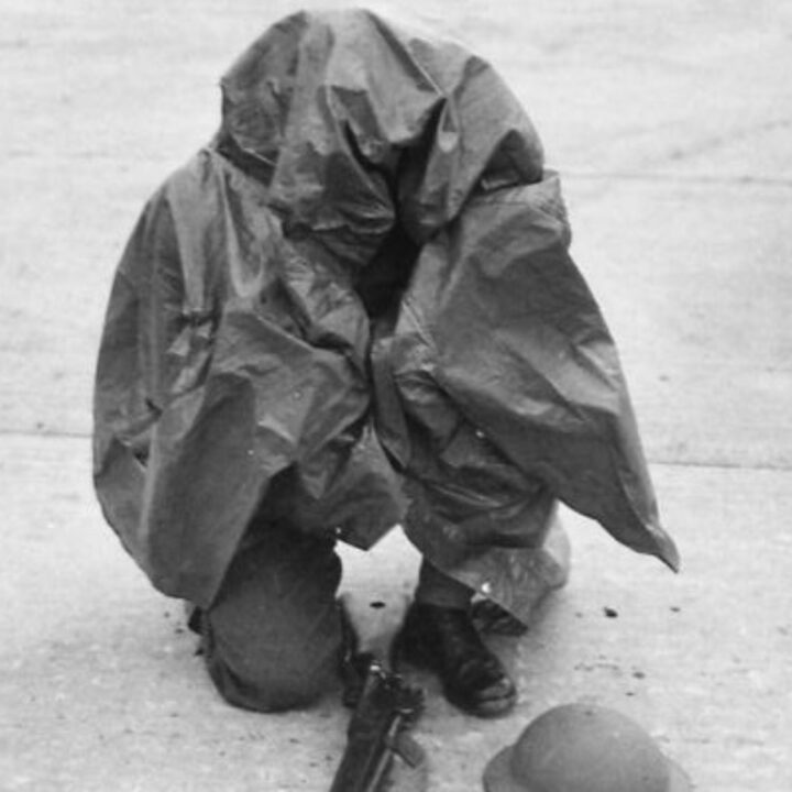 A soldier hiding under a cape demonstrates the wrong thing to do during a spray gas attack. These illustrative photographs are from a demonstration held in Northern Ireland.